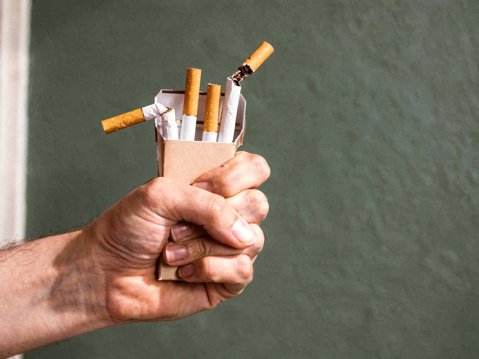 Main qui écrase un paquet de cigarettes, arrêt du tabac par l'hypnose à Lyon